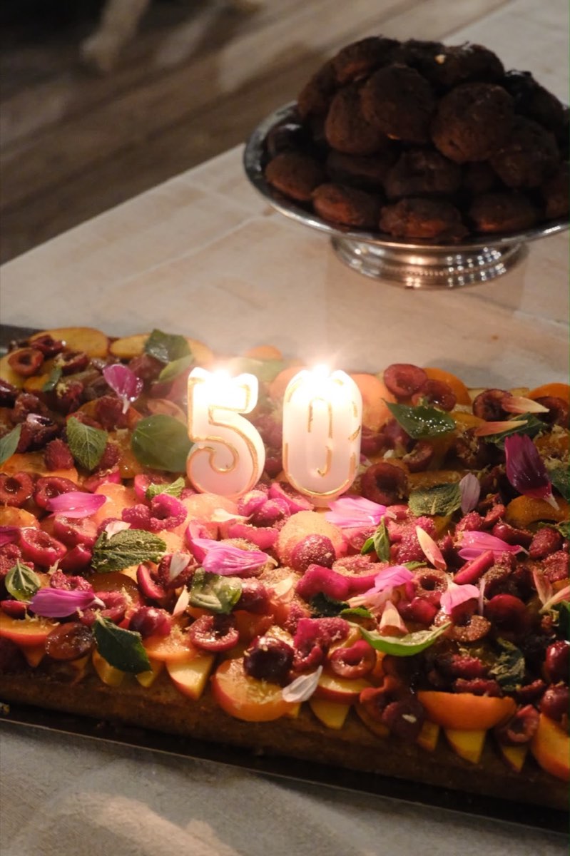 Grand gâteau d'anniversaire de tablée sud entièrement recouvert de fruits frais, de fleurs comestibles et de menthe